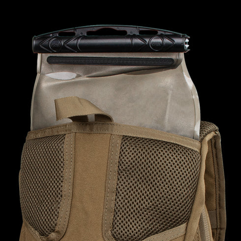A Condor Hydration Backpack 8L in tan, featuring mesh detailing, has a tactical bladder with a black slider partially inserted into its back pocket.